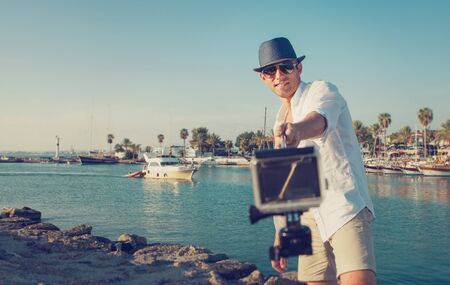 handsome man with action camera take a selfie photo in the tropical sea bayの写真素材