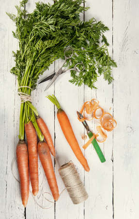 A bunch of fresh carrots on white wooden backgroundの写真素材