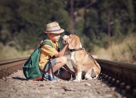 Little boy with his dog sitting on the railwayの写真素材