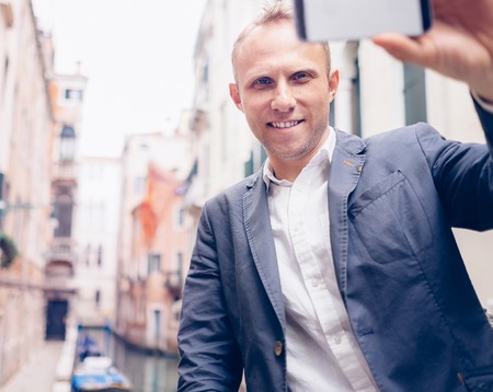 Smiling man take a selfie tourist photo on the Venice  backgroundの写真素材