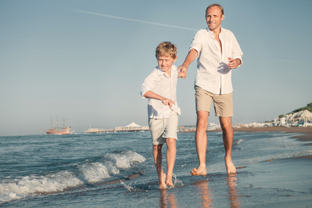 Father with son running together on the sea surf lineの写真素材