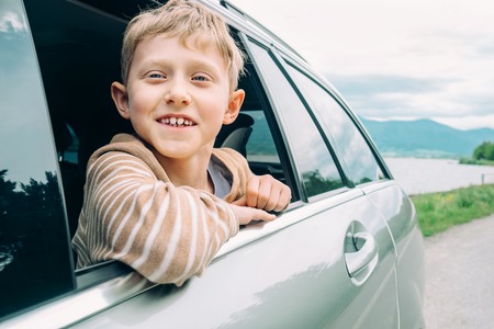 Happy boy look out from window carの写真素材