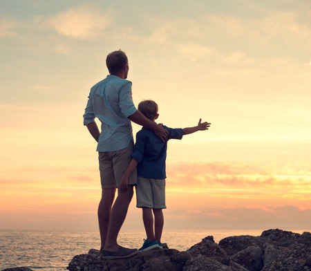 Father and son looking on sunset at the seaの写真素材