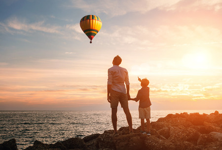 Father with son look on the balloon on the sea coastの写真素材