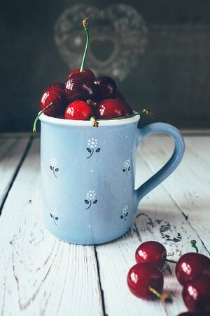 Fresh cherries are in blue mugの写真素材