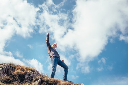 Happy man triumph his climb on the top of mountainの写真素材