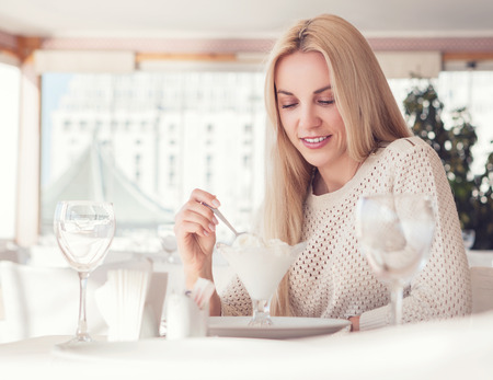 Young woman in sunny restaurant with ice-cream desertの写真素材