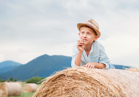 Dreaming boy lying on the rolling haystackの写真素材