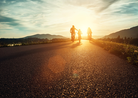 ?yclists family traveling on the road at sunsetの写真素材