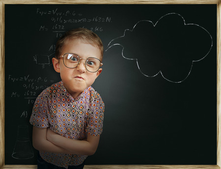 Emotional pupil boy near chalkboardの写真素材