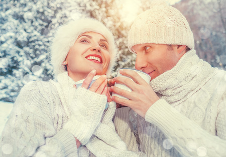 Cozy dressed couple in love drink hot of tea in winter forestの写真素材