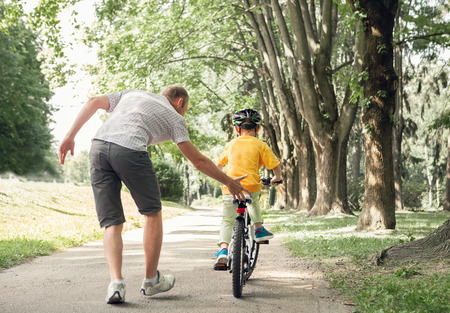 Father learn his little son to ride a bicycleの写真素材