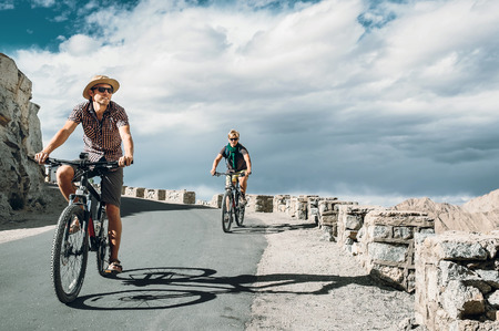 Two bicykle travelers on the mountain road in Himalayaの写真素材