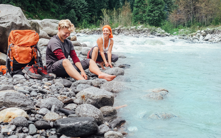 Two travelers refreshing on the mountain riversideの写真素材
