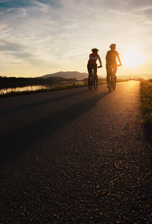 Two cyclists are on sunset roadの写真素材