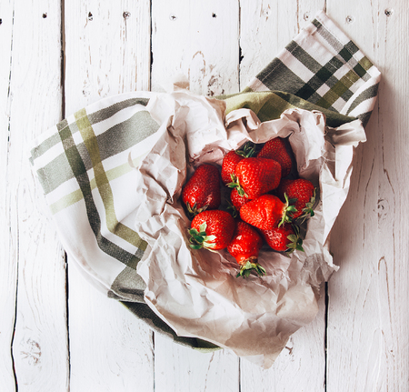 Handful of fresh strawberries is on white wooden tableの写真素材