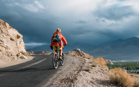 Bike tourist rides on Himalaya mountain road on way to buddist monasteryの写真素材
