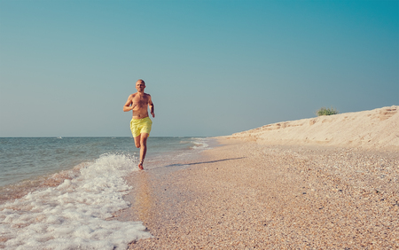 Man runs on the sea surf line の写真素材