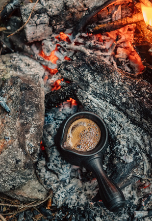 Fresh turkish coffe making in clay cezve on the campfire coalsの写真素材