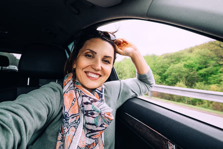 Happy smiling woman sits in autoの写真素材