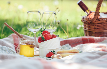 Two wine goblets, fresh strawberry, honey and wine are served for summer romantic picnicの写真素材