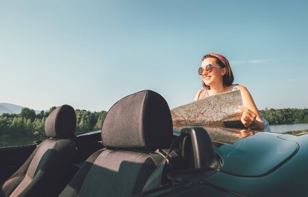 Woman reads a roads map during her auto travel