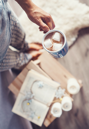 Woman hand with cup of hot chocolate: cozy home interior, Christmas time moodの写真素材