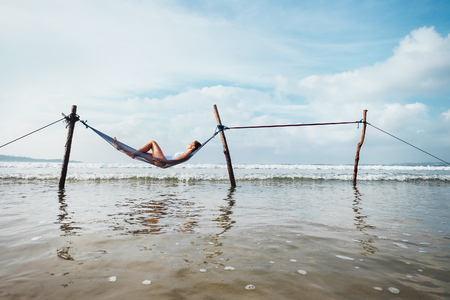 Woman relax lying in hammock swing over the ocean surf lineの写真素材