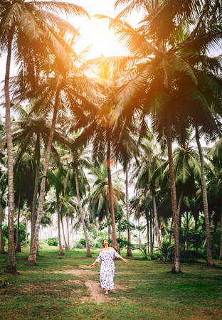 Woman in long dress walk under palm trees. Romantic island vacationの写真素材