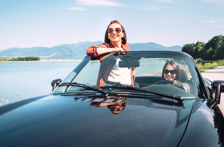 Two female friends travel togehetr by cabriolet car
