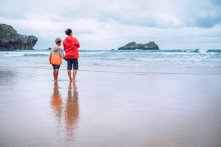 Mother and son look on waves on ocean coast line after the stormの写真素材
