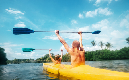 Father and son are sailing in the canoe in lagoon in sunny dayの写真素材