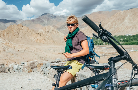 Young man bike traveler rest on high mountain road in Himalayaの写真素材