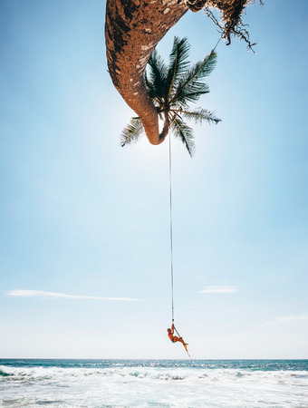 Little boy dangles on tropical palm tree swing, Sri Lanka beachの写真素材