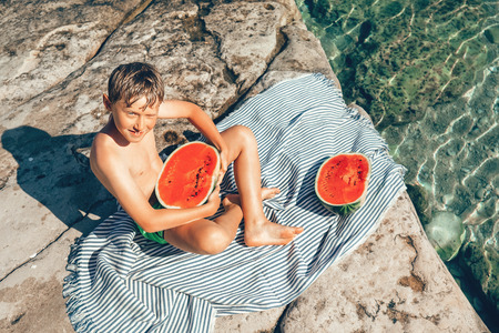 Summer plesuares: boy ready to eat big watermelon after swimming in the sea