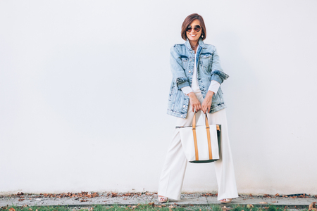Elegant woman dressed in oversize denim jacket and wide white trousersの写真素材