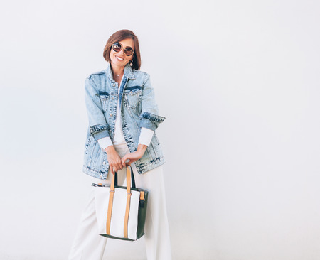 Woman in elegant outfit with oversize denim jacket and shopper bagの写真素材