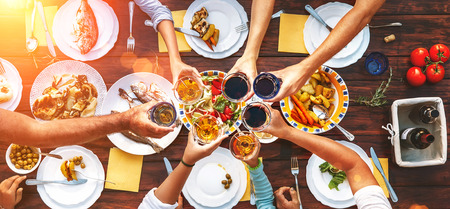 Big family dinner. Vertical top view on served table and hands with clinking gobletsの写真素材