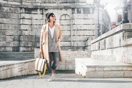 Woman in trend autumn multilayered outfit walks on city old streetの写真素材