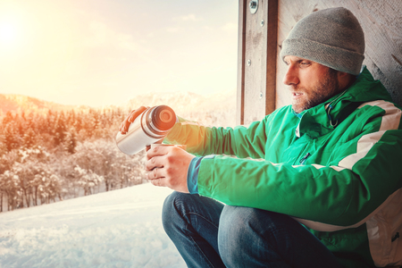 Man drinks a hot drink worker ot traveler on open winter airの写真素材