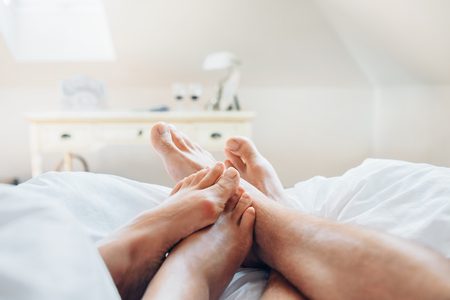 Couple in love meet morning in bed. Close up image man and woman feetsの写真素材