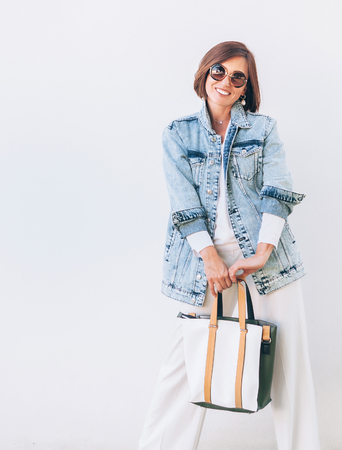 Elegant woman dressed in oversize denim jacket and wide white trousersの写真素材