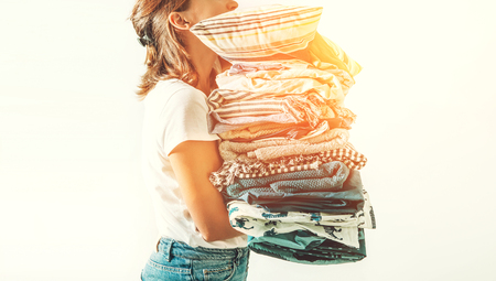 Woman with a big pile blue and beige blankets, towels and other home textileの写真素材