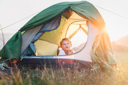 Boy rest in camping tent. Sunset time in natureの写真素材