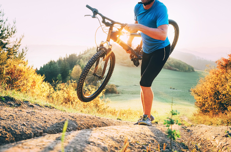Cyclo-cross competition member Man mountain biker carrying his bike up on hill topの写真素材