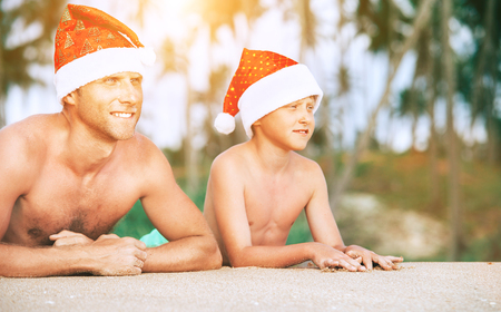 Father and son in Sants hats portrait on tropical bisland beachの写真素材