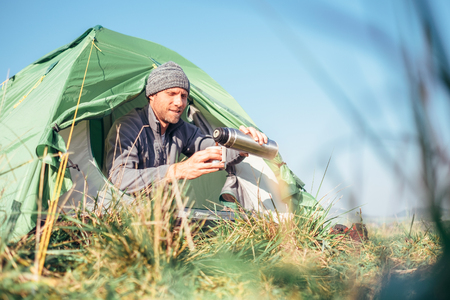 Man sits in tent and drinks hot teaの写真素材