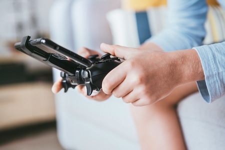 Child hands with game controller connected with smartphone close up image.