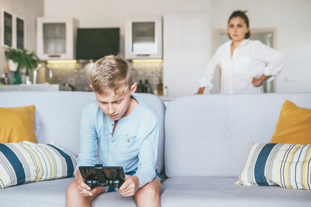 Mother unhappy with teenager son who spent his free time with electronic devices and games.の写真素材