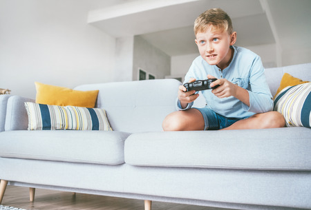 Preteen boy enthusiastically plays the game console